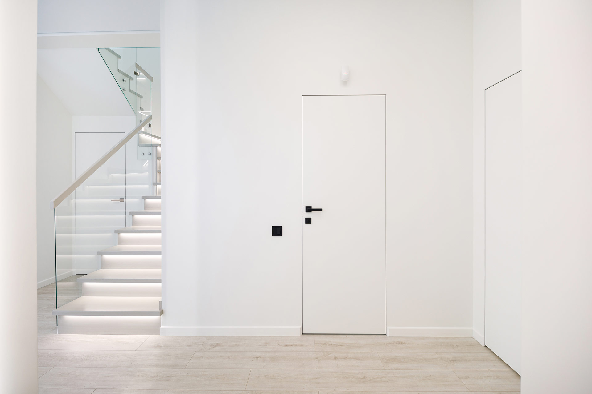 Moderne weiße rahmenlose Innentür mit schwarzer Drückergarnitur