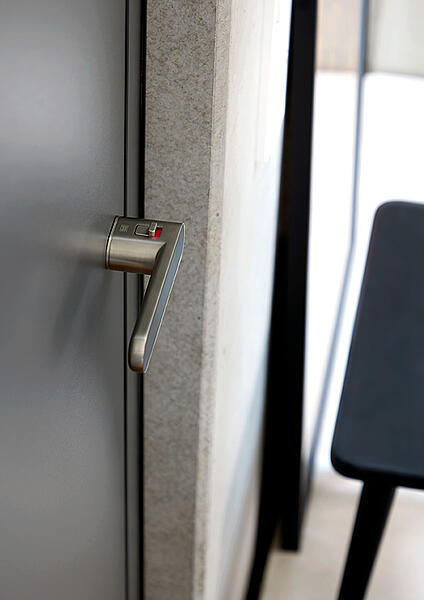 Moderner Türdrücker in Edelstahl-Optik mit smart2lock Technik an grauer Innentür 