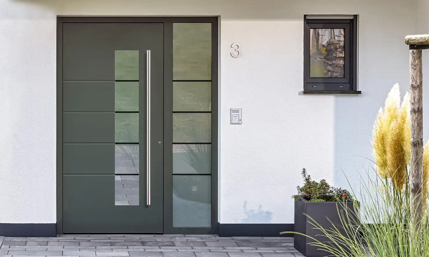 Dunkelgraue Haustür mit schmalem Glasausschnitt, langem Edelstahlgriff und verglastem Seitenteil