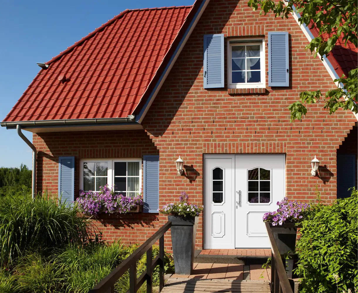 Weiße zweiflügelige Haustür mit Glasausschnitten und Zierelementen an einem roten Klinkerhaus