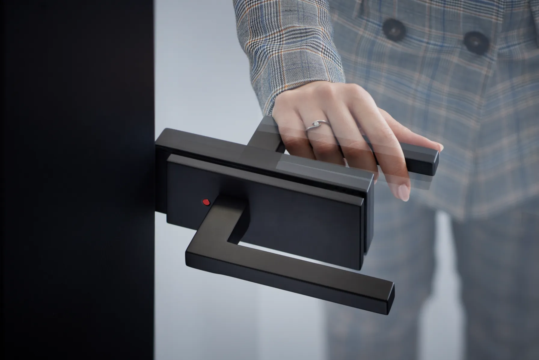 Hand betätigt einen schwarzen, kantigen Türdrücker mit integrierter Verriegelung und roter Anzeige